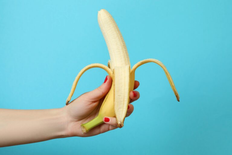 Female hand hold banana on blue background