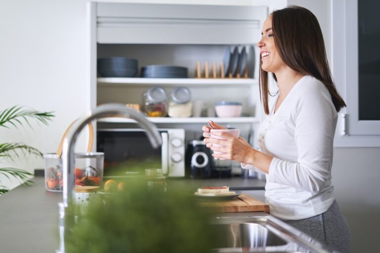 Woman drinking from cup in kitchen