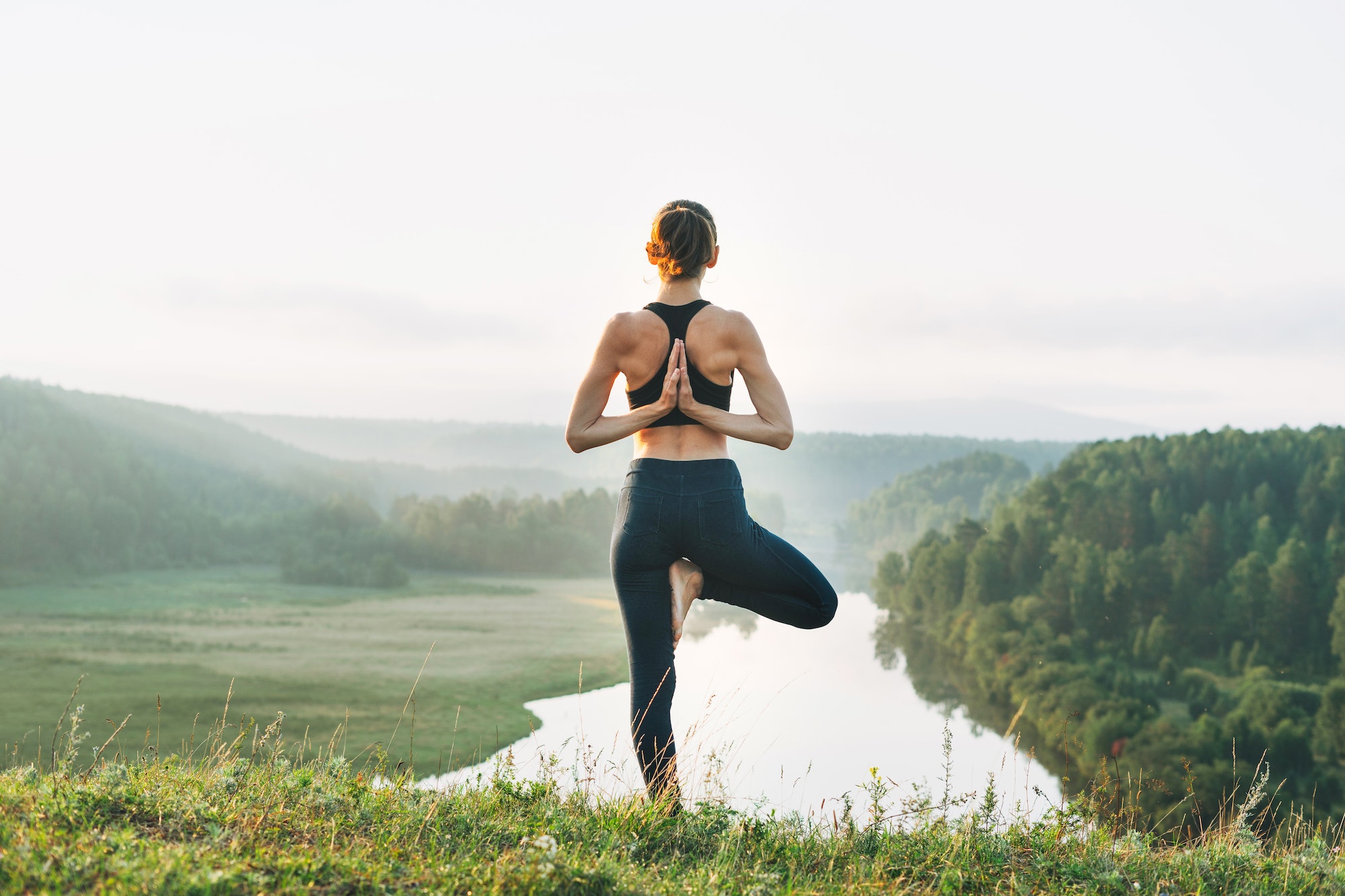 Young woman girl practice yoga looking on beautiful landscape on early morning