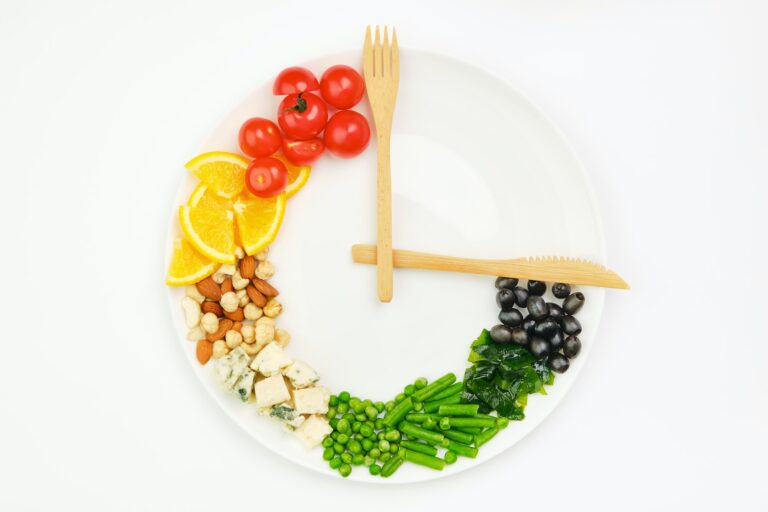 Colorful food and cutlery arranged in the form of a clock on a plate. Intermittent fasting concept.
